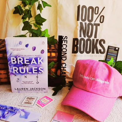 April 2025 Nook Box featuring Break the Rules by Lauren Jackson with pink Only Judy Can Judge Me cap, bookish tote and romance reader accessories.