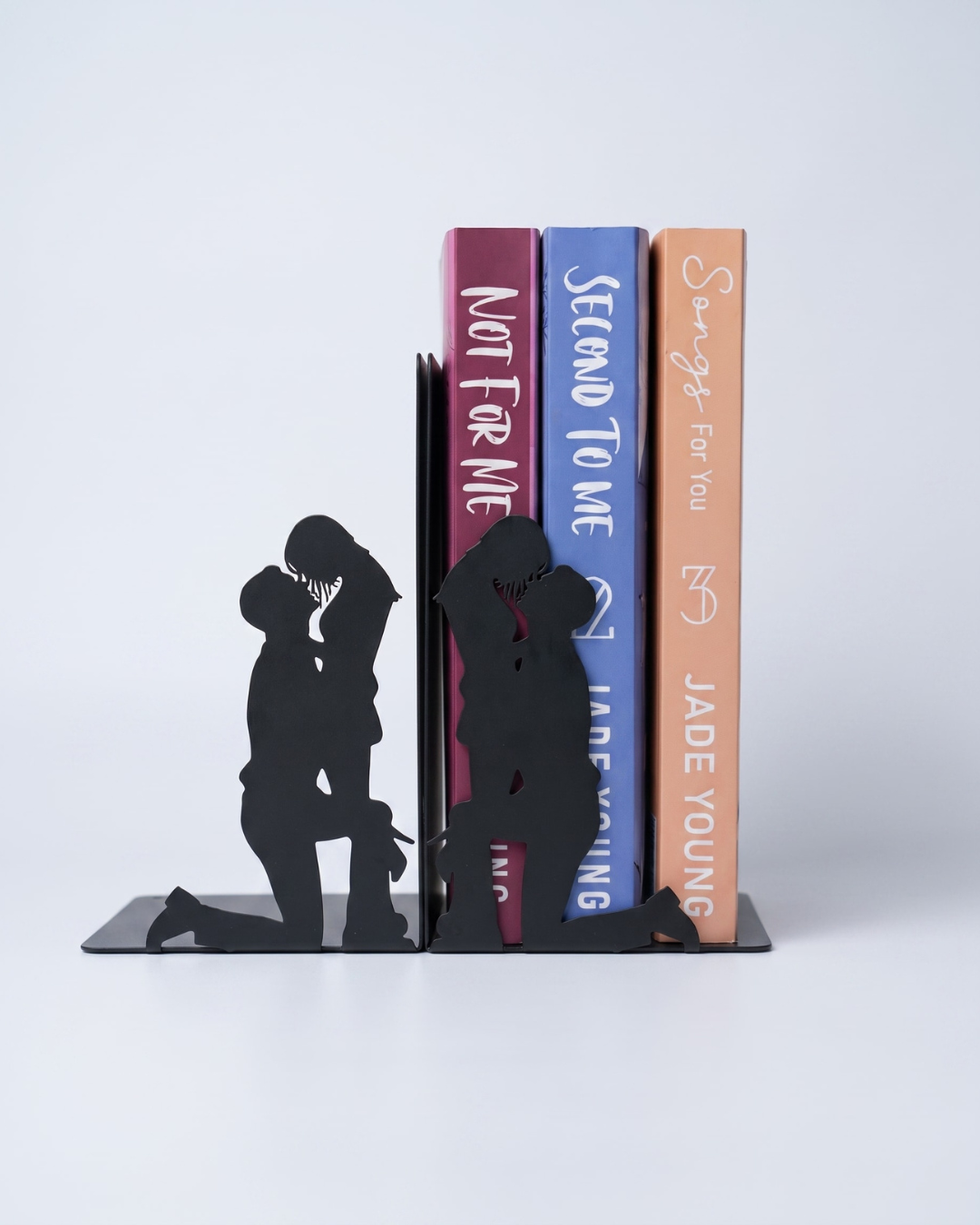 Black metal romantic couple silhouette bookends supporting a collection of romance novels on the side.