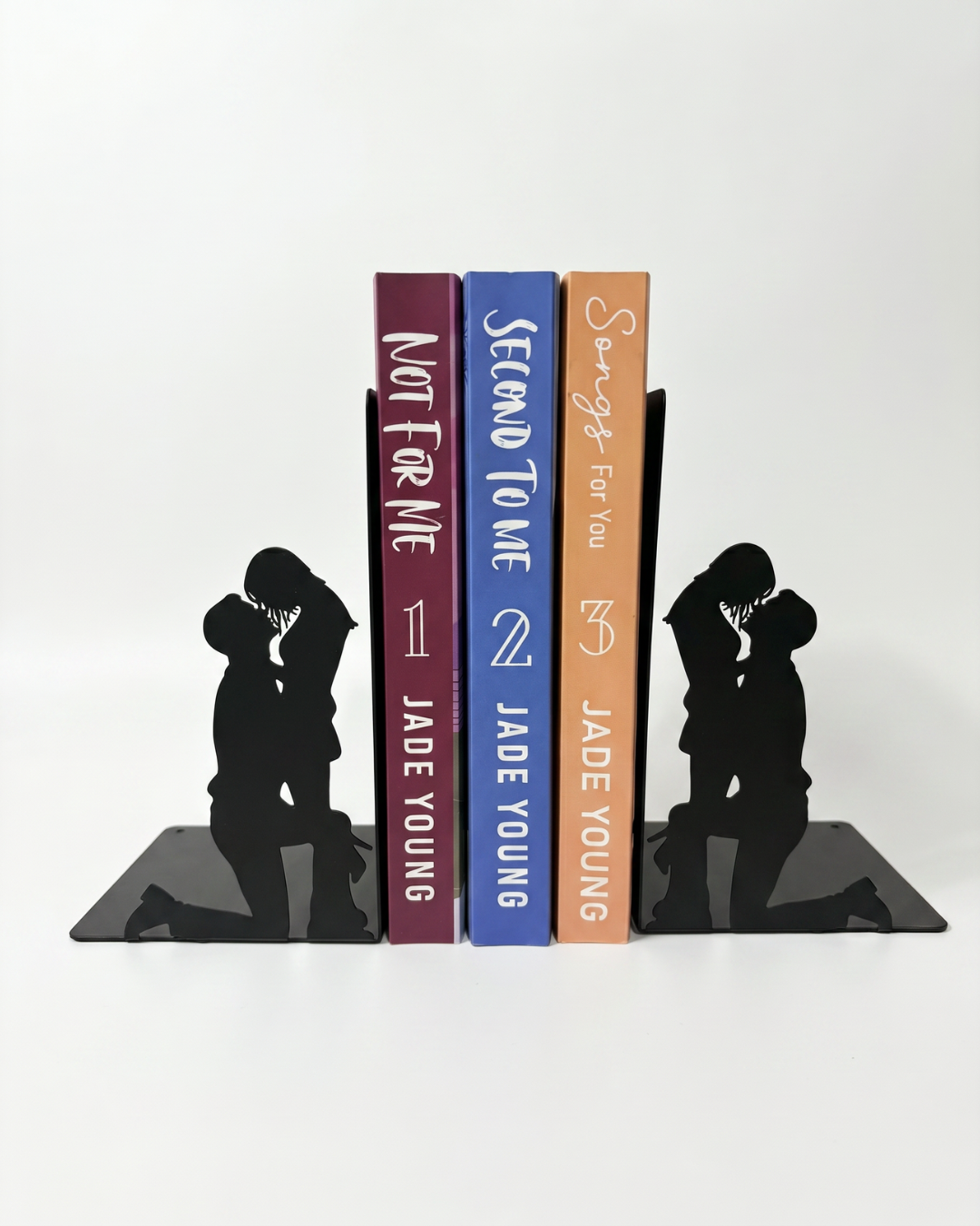 Black romantic silhouette bookends holding three romance books upright on a bookshelf.