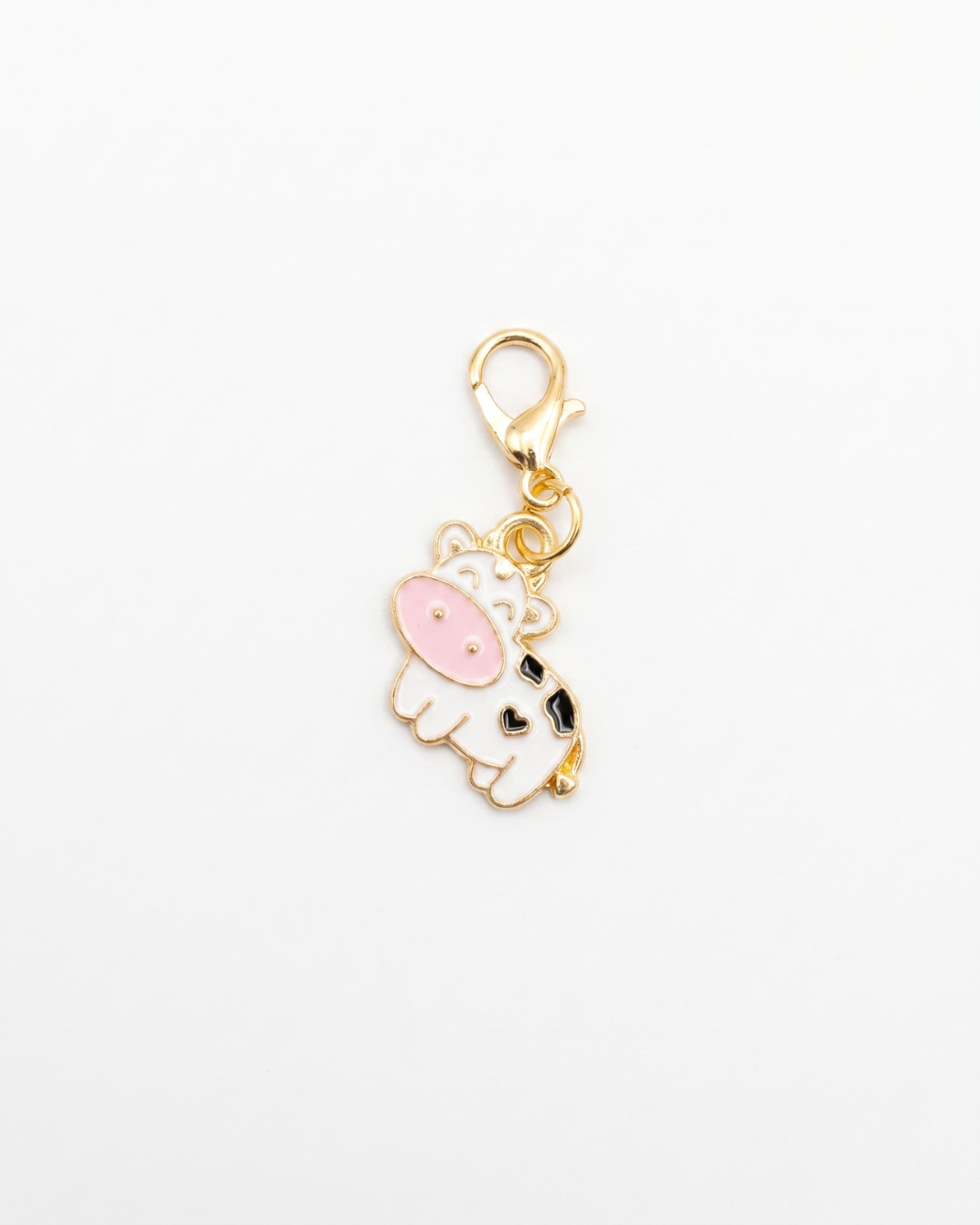 Golden and enamel charm with lobster hook showing a white cow with black spots