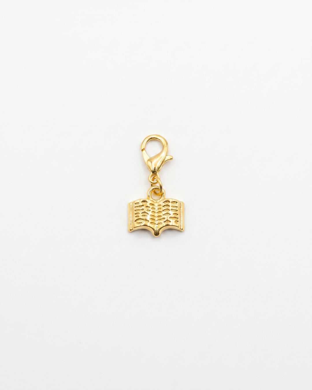 Golden charm with lobster hook showing a book with lines representing writing