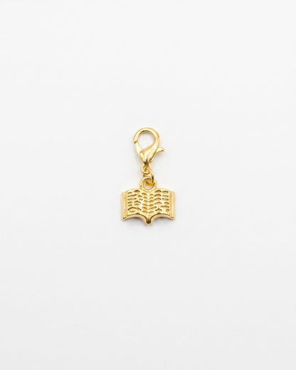 Golden charm with lobster hook showing a book with lines representing writing