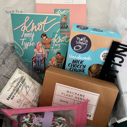 July 2025 Nook Box featuring Knot My Type by Evie Mitchell with macrame plant hanger, bamboo charcoal dehumidifier, cookies and bookish accessories.