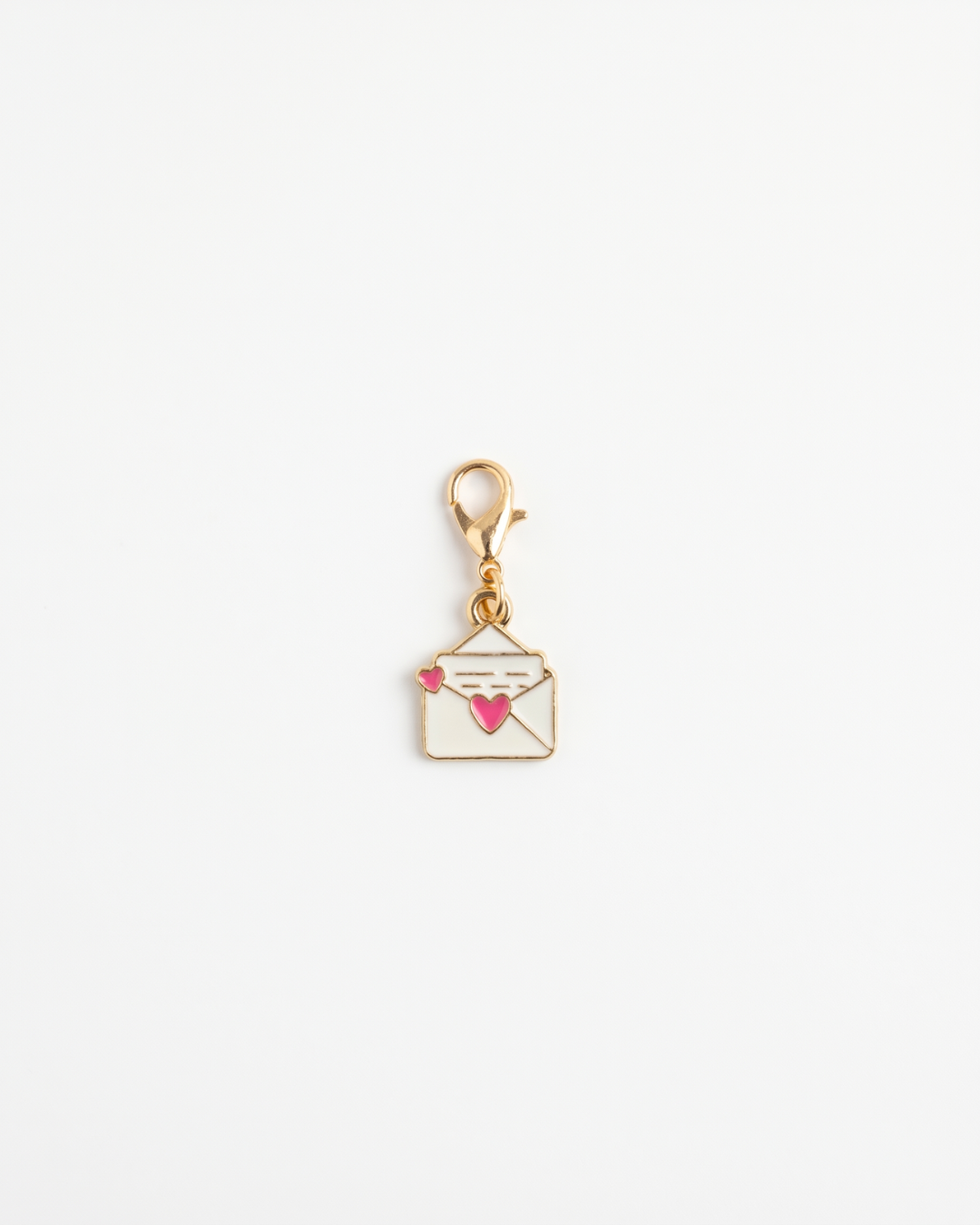 Golden and enamel charm with lobster hook showing a letter with a heart on the opening