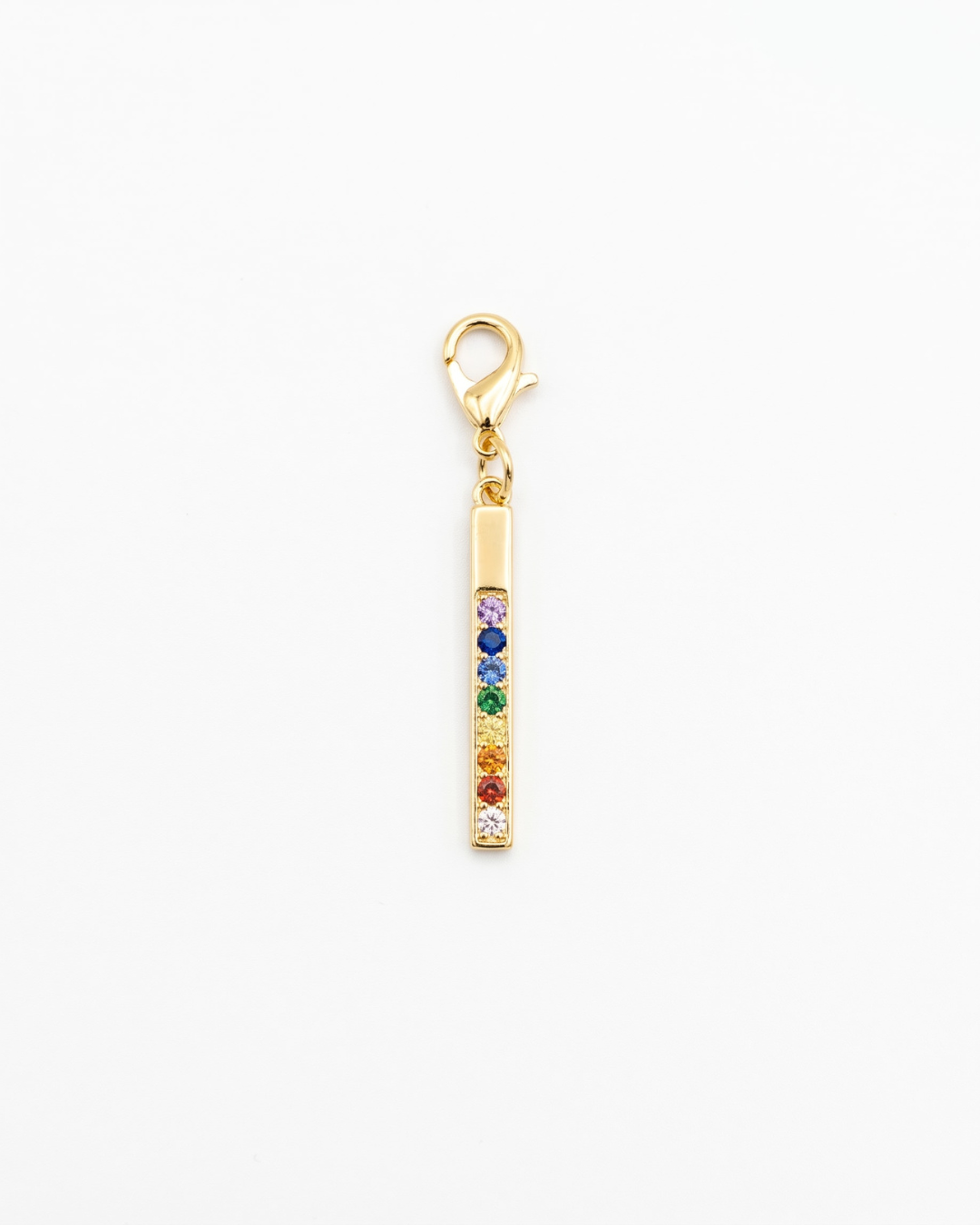 Golden charm with lobster hook showing rainbow ziconia in a bar pendant