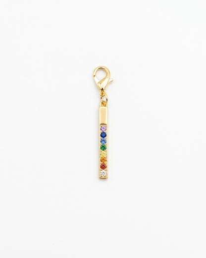 Golden charm with lobster hook showing rainbow ziconia in a bar pendant