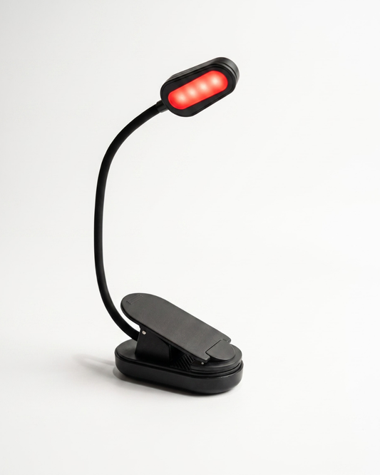 Black clip-on rechargeable reading light with adjustable flexible neck and red LED illumination angled downward for reading in bed.
