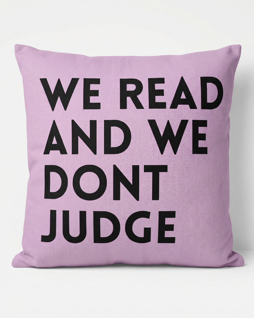 Purple Cushion that reads We Read and We Dont Judge